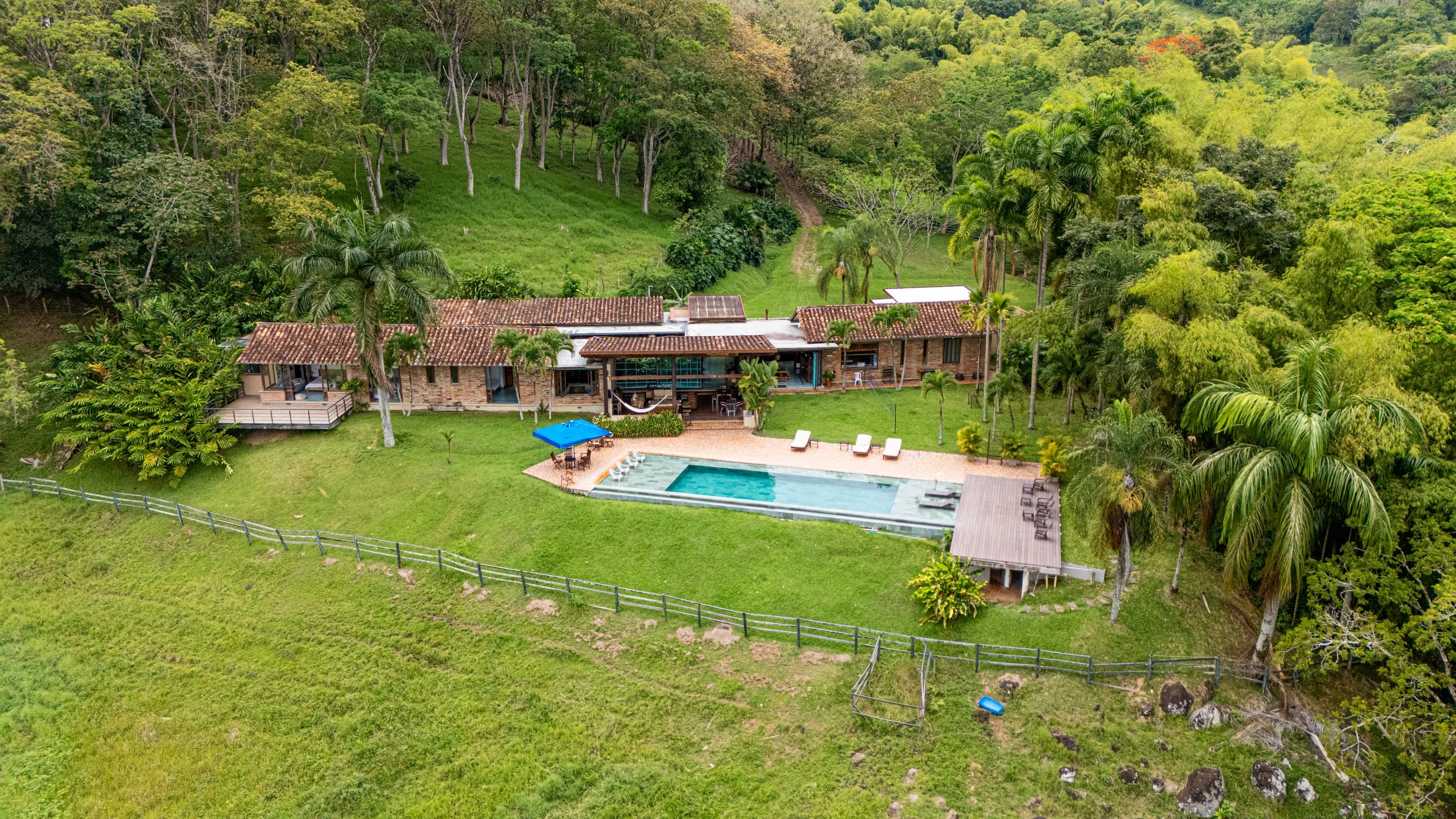 Vista aérea de Finca Cuatro Gatos: la casa, la piscina y los jardines rodeados de montañas