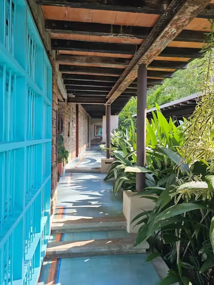 Corredor exterior con rejas turquesa y plantas tropicales