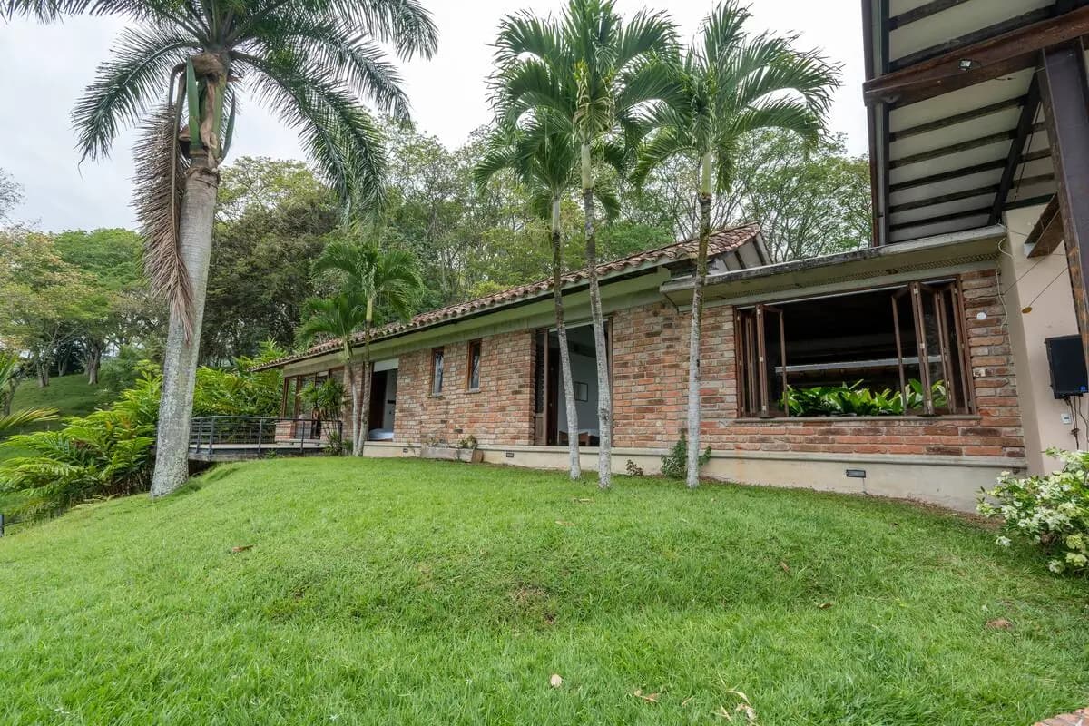 Casa de ladrillo de Finca Cuatro Gatos entre palmeras y jardín