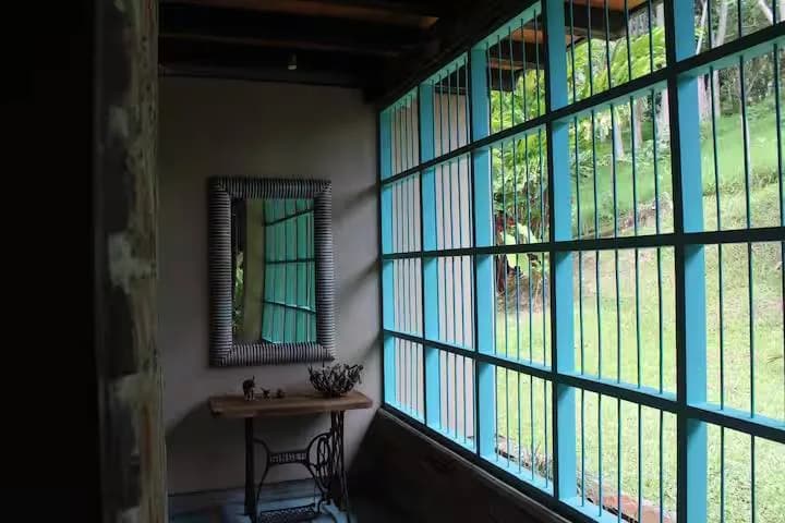 Ventanal turquesa con vista al jardín desde el interior de la casa